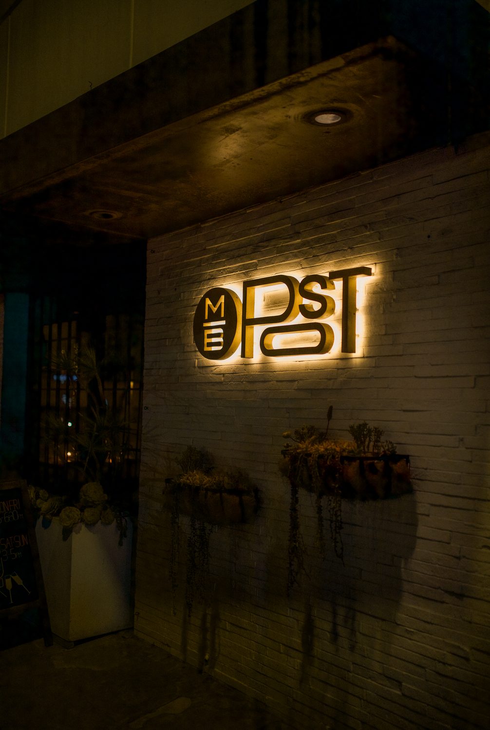 The lit M.B. Post sign at the front of the restaurant at night